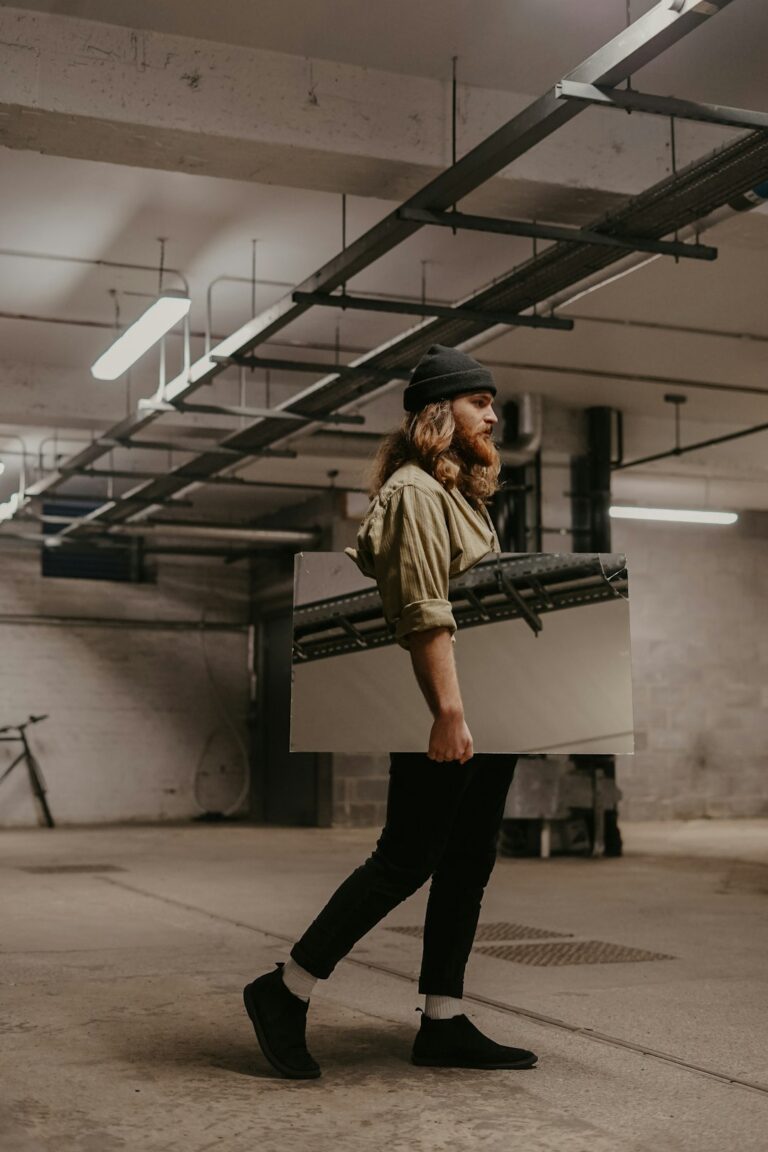 Person lifting a cardboard box close to the body with bent knees and a neutral spine.